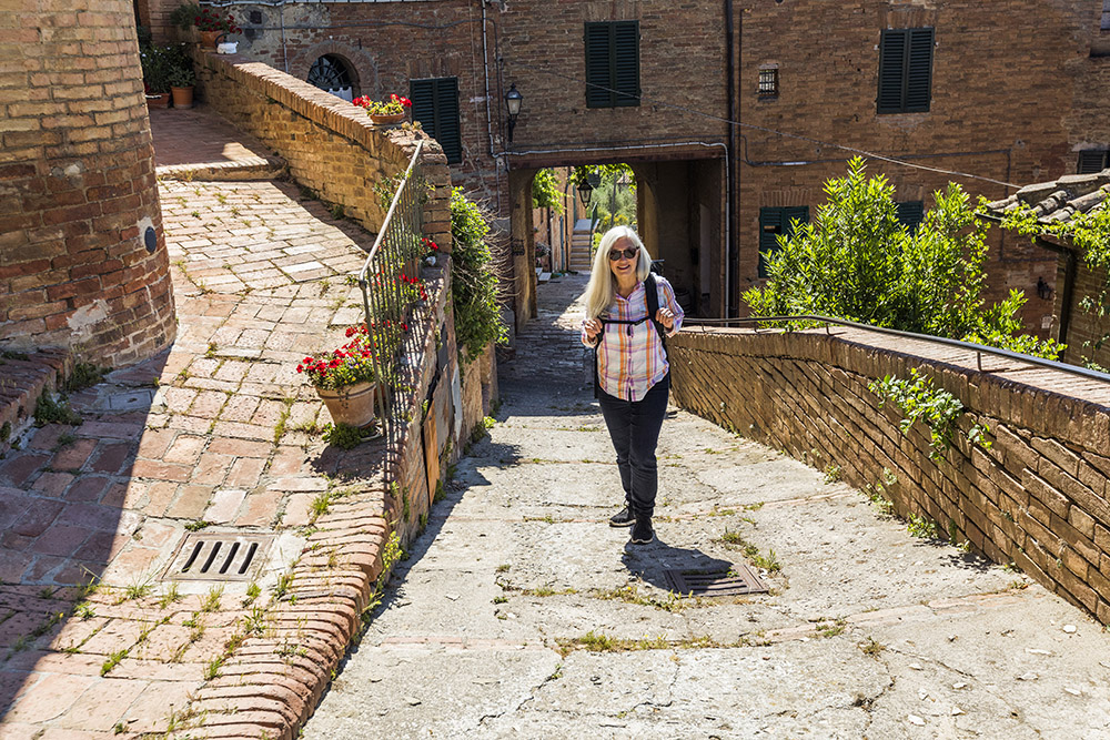 En dame som vandrer gjennom en gammelby i Toscana